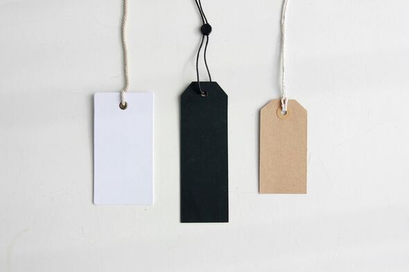 Three blank product tags in white, black, and kraft paper hanging against a white background.