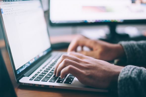 a close-up photo of hands typing on a laptop keyboard